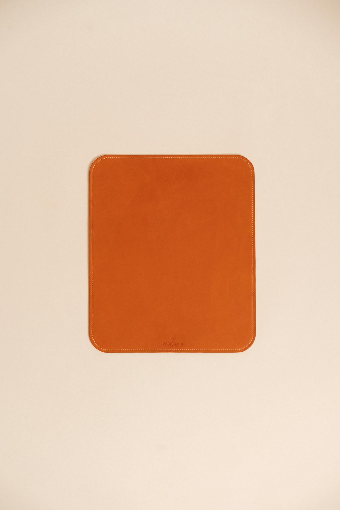 A stylish brown leather desk mat on a minimalistic beige surface, perfect for modern office spaces.