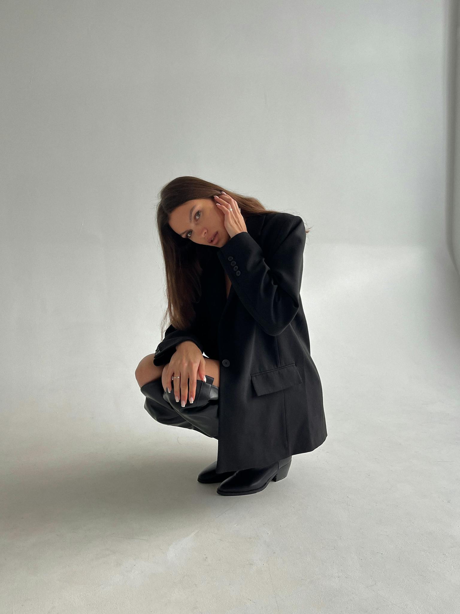 Stylish woman in black blazer posing indoors, showcasing modern fashion.